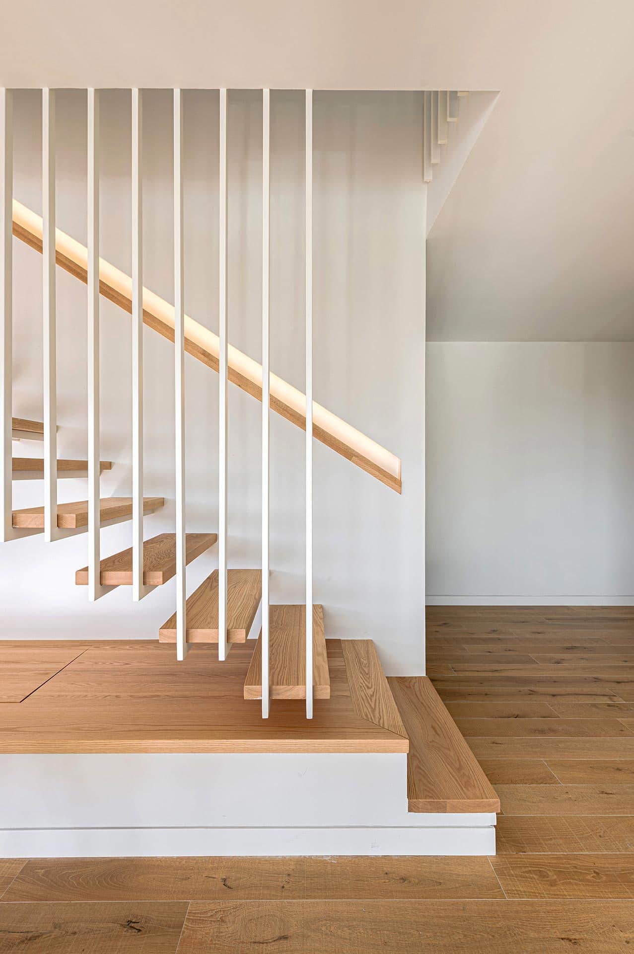 Escalera ligera con pasamanos empotrado y peldaños de madera de casa diseñada por Moah Arquitectos en Cantabria