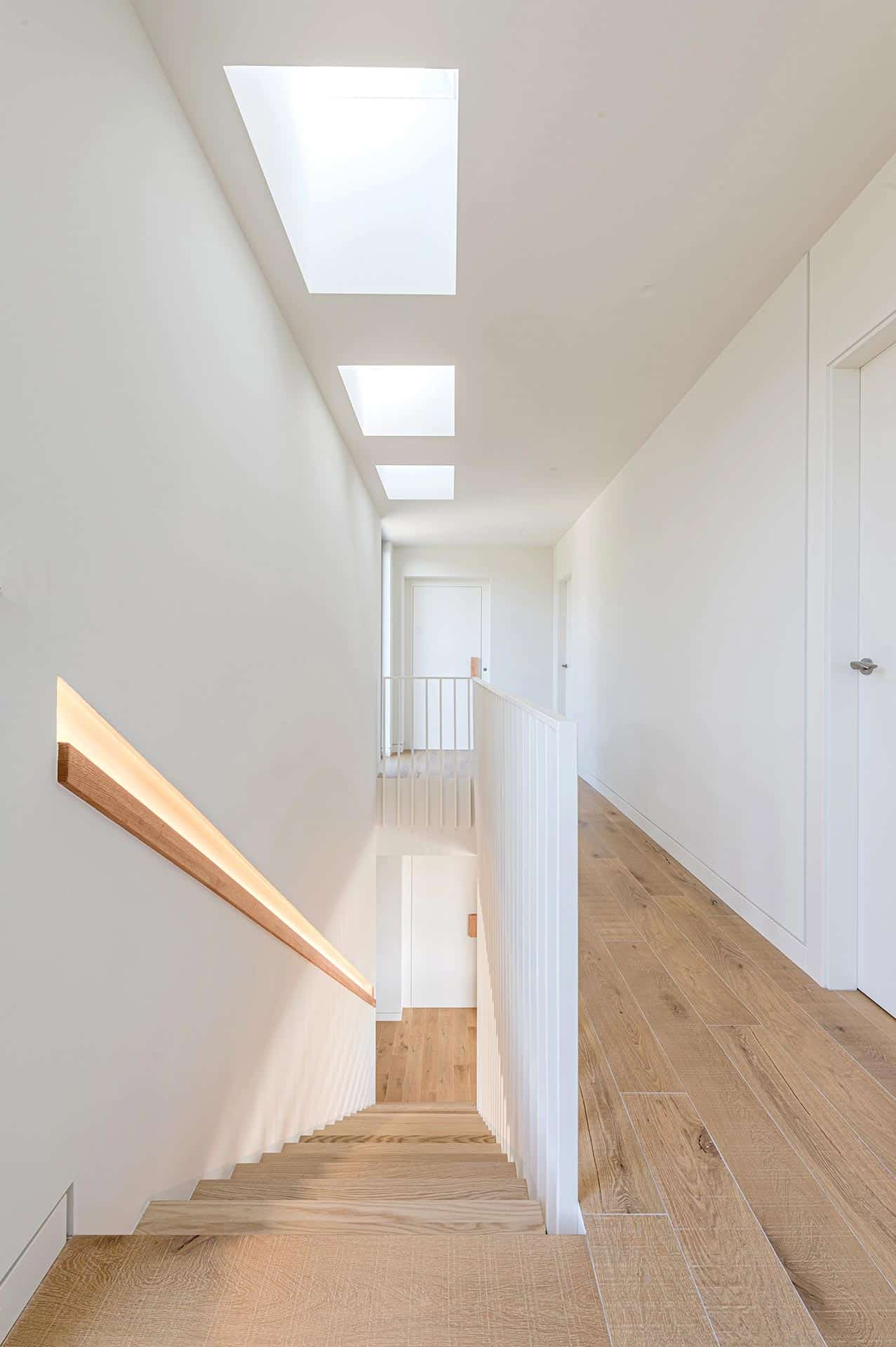 Escalera de madera con luz cenital en vivienda unifamiliar diseñada por Moah Arquitectos en Loredo
