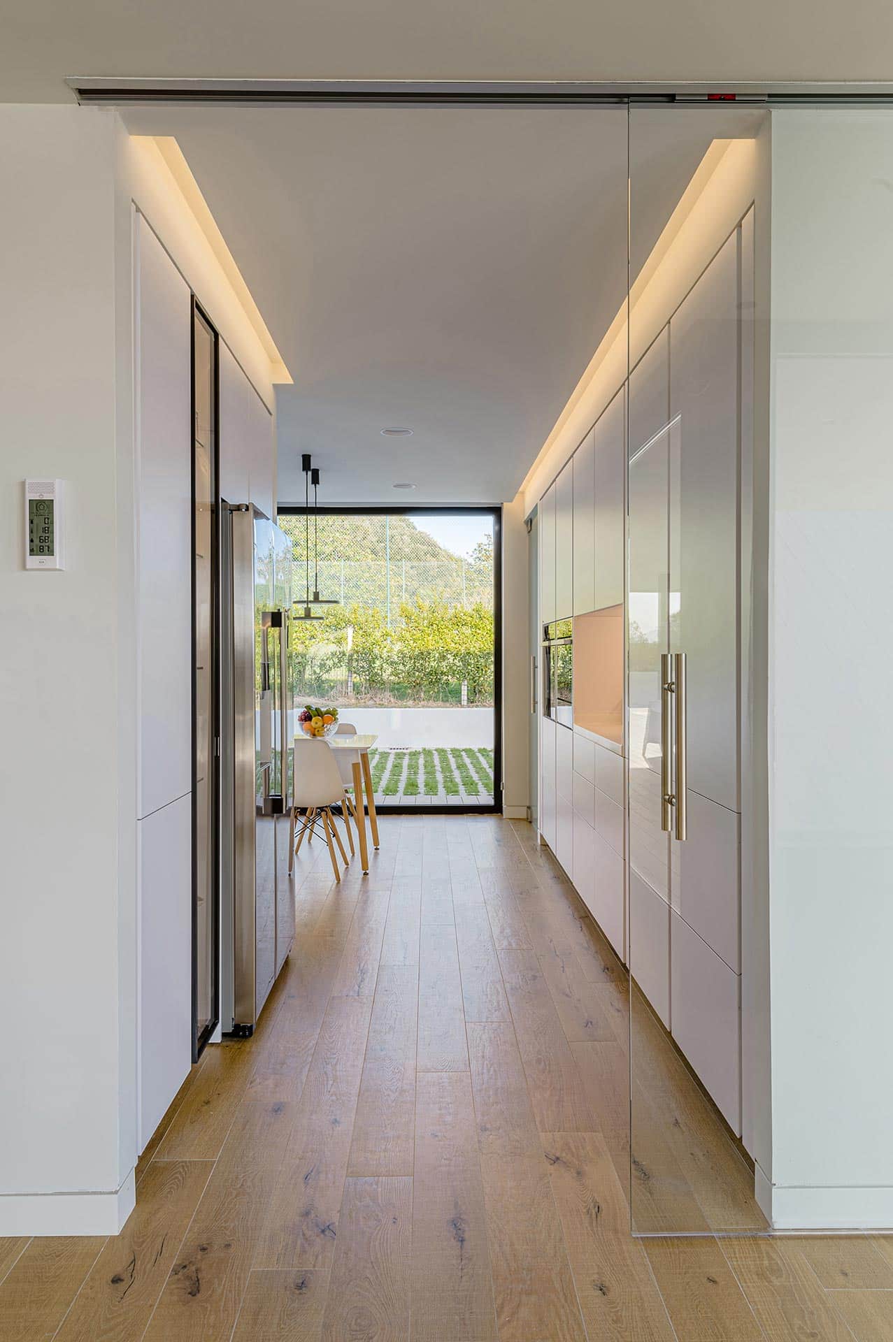 White kitchen with glass door in modern house designed by Moah Architects in Loredo