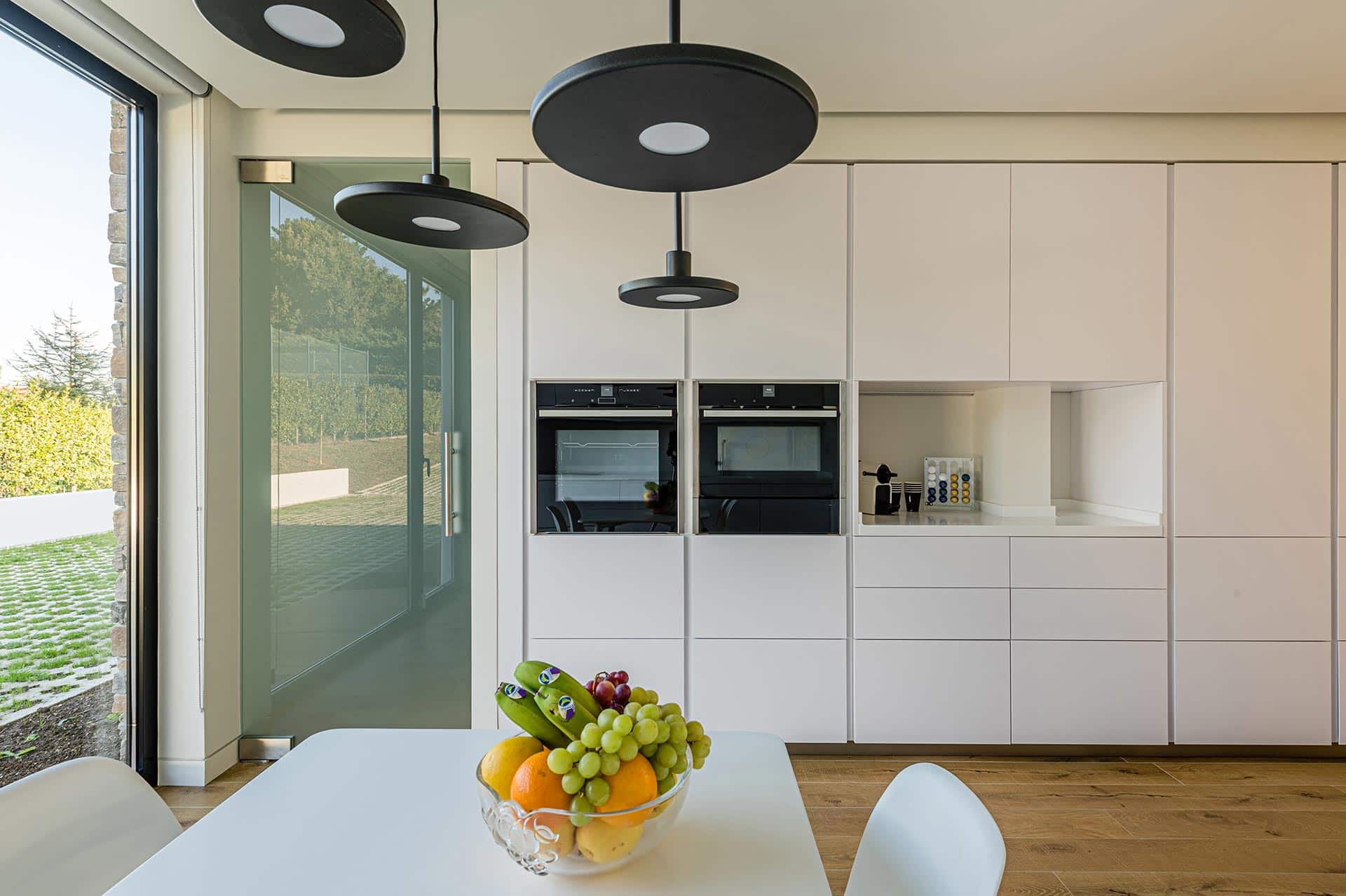 Interior de cocina blanca con lampara negra en vivienda moderna diseñada por Moah Arquitectos en Cantabria