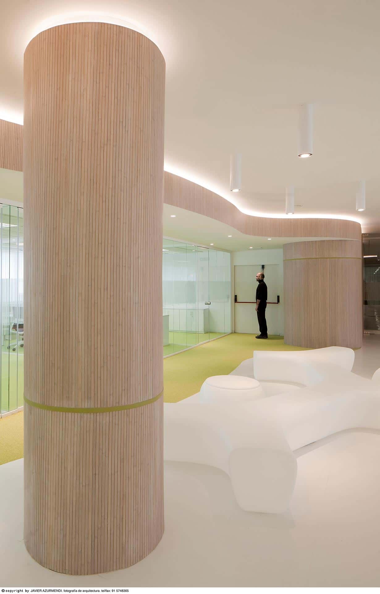 Columna de madera y suelo blanco de la reforma interior de oficina diseñada por Moah Arquitectos en Cantabria