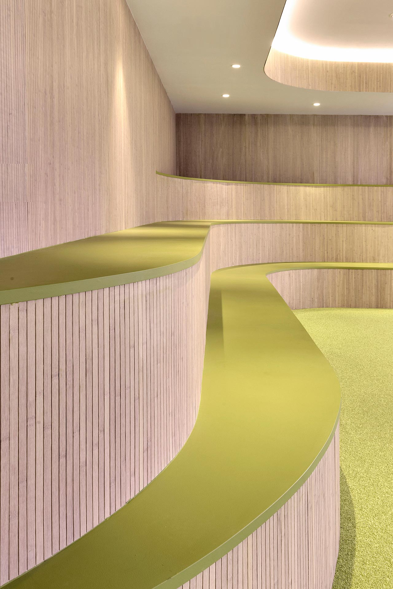 Gradas de madera y suelo verde en reforma de oficina del CISE diseñado por Moah Arquitectos en Santander