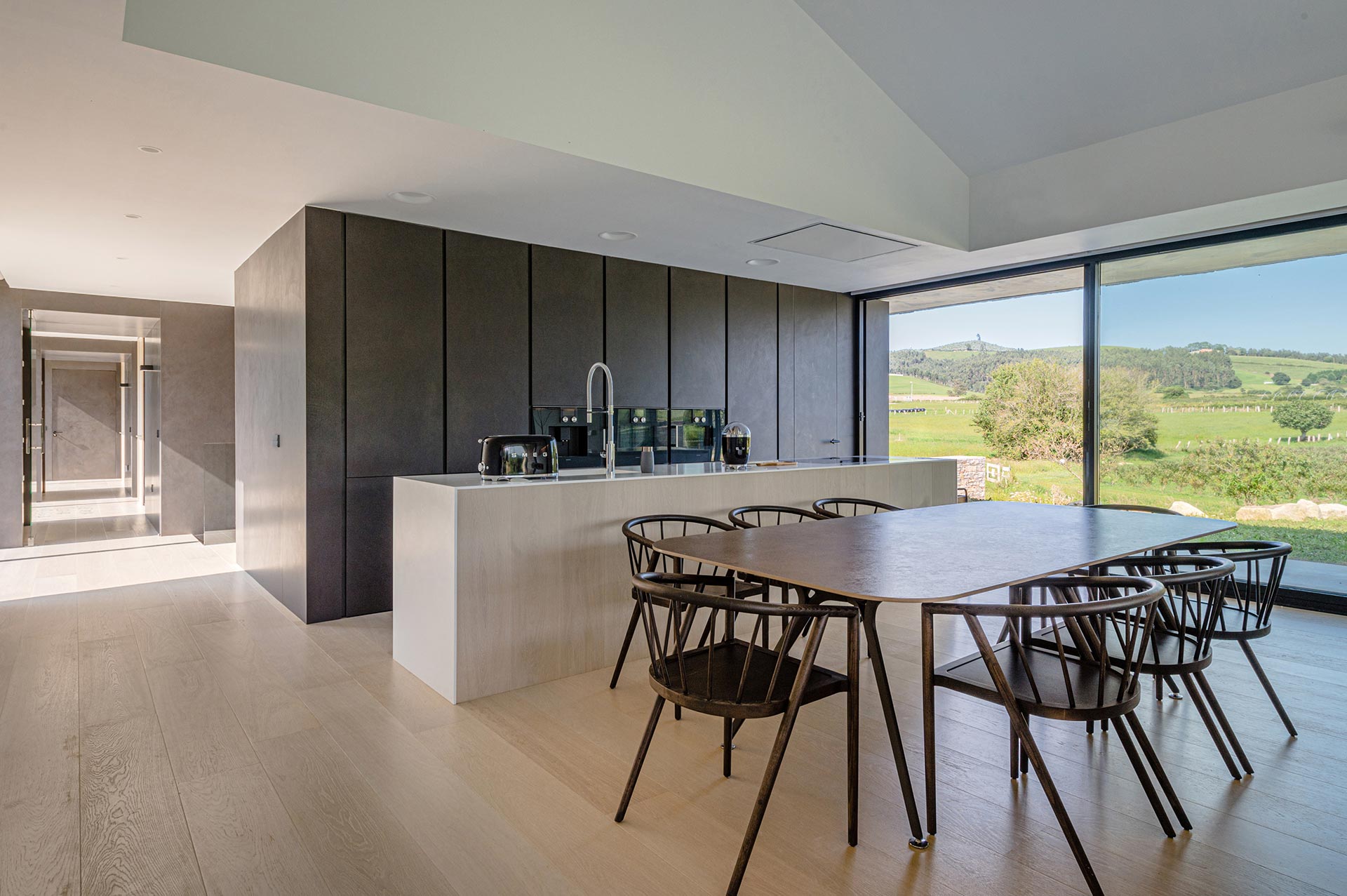 Cocina minimalista y comedor de casa moderna diseñada por Moah Arquitectos en Cantabria