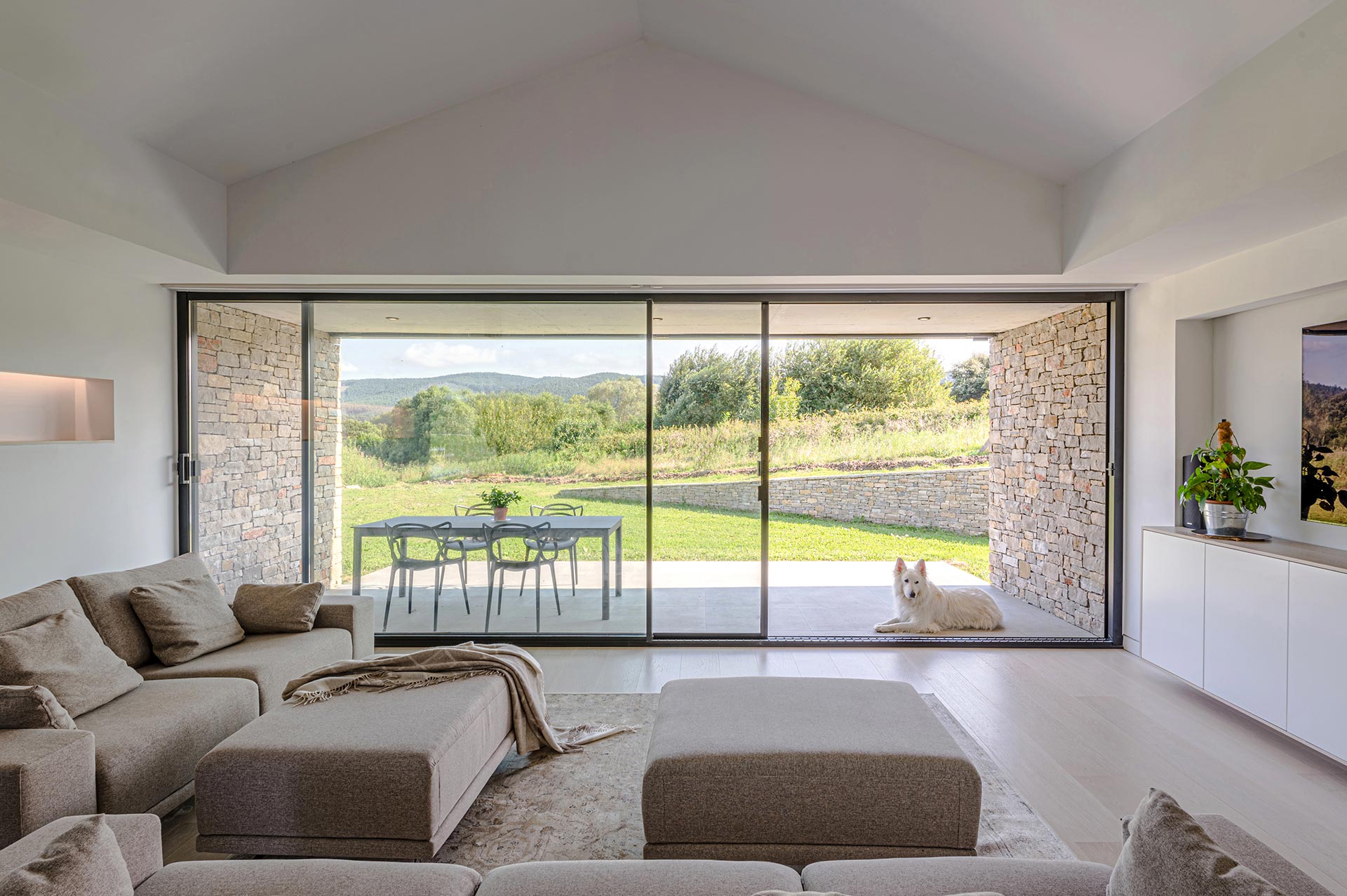 Salón minimalista con grandes cristaleras en casa moderna diseñada por Moah Diseño de Interiores en Cantabria