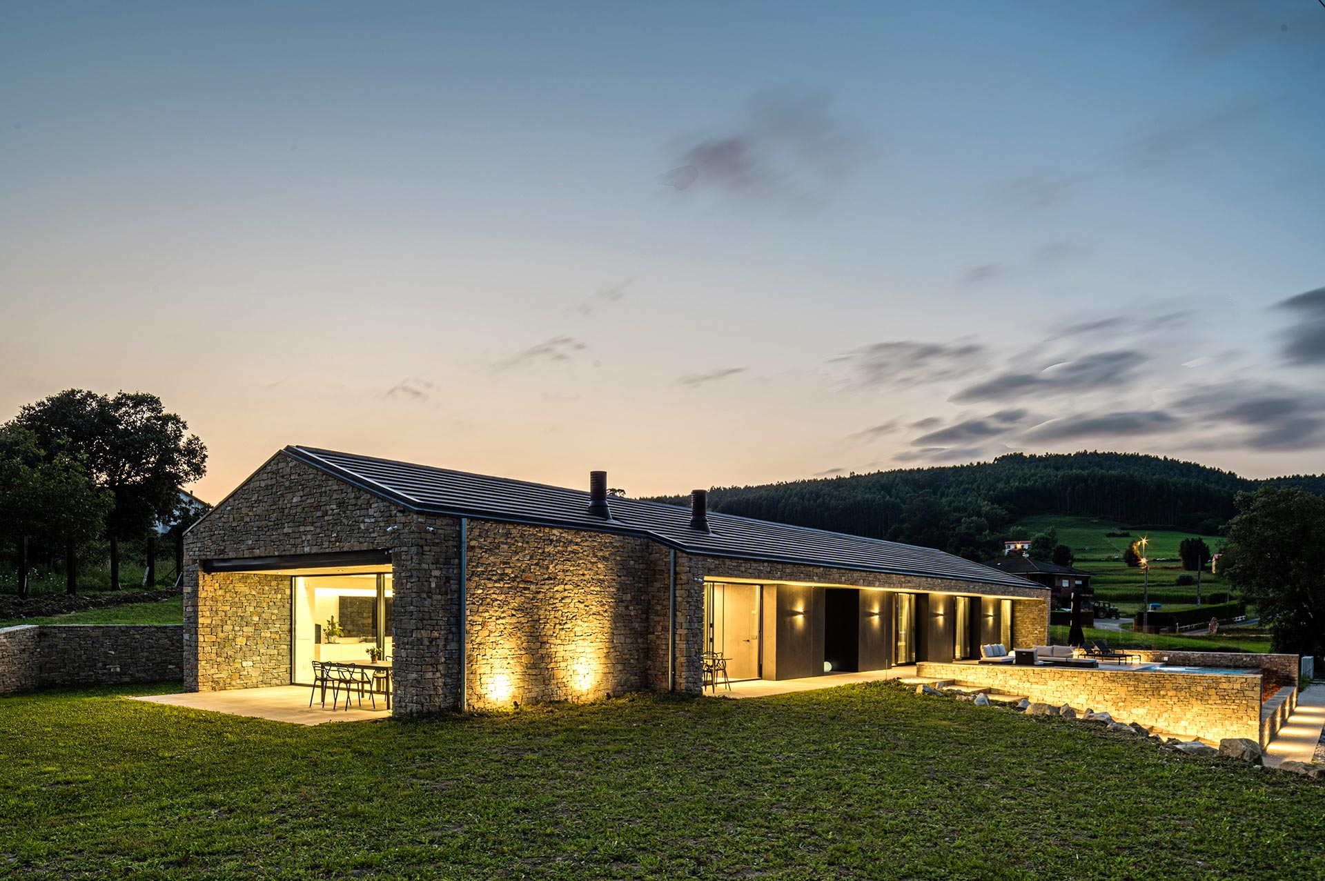 Iluminación exterior de casa moderna de piedra diseñada por Moah Arquitectos en Bareyo