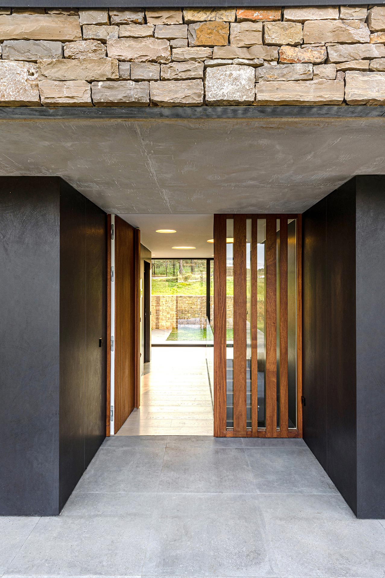 Puerta de entrada de madera de casa moderna de piedra diseñada por Moah Diseñador de Interiores en Cantabria