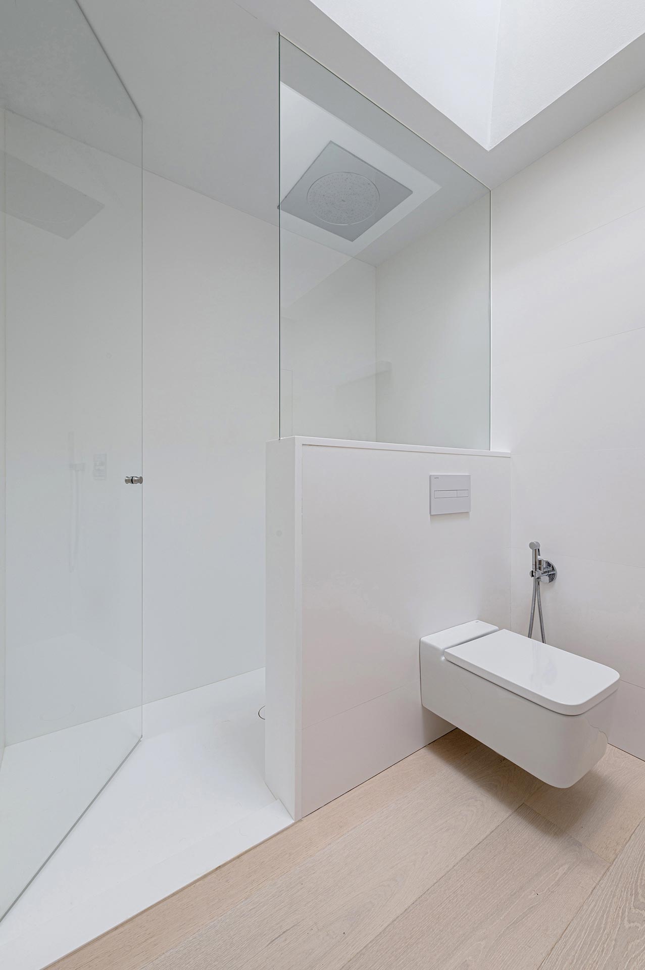 Baño en gres porcelánico blanco en casa moderna diseñada por Moah Arquitectos en Cantabria