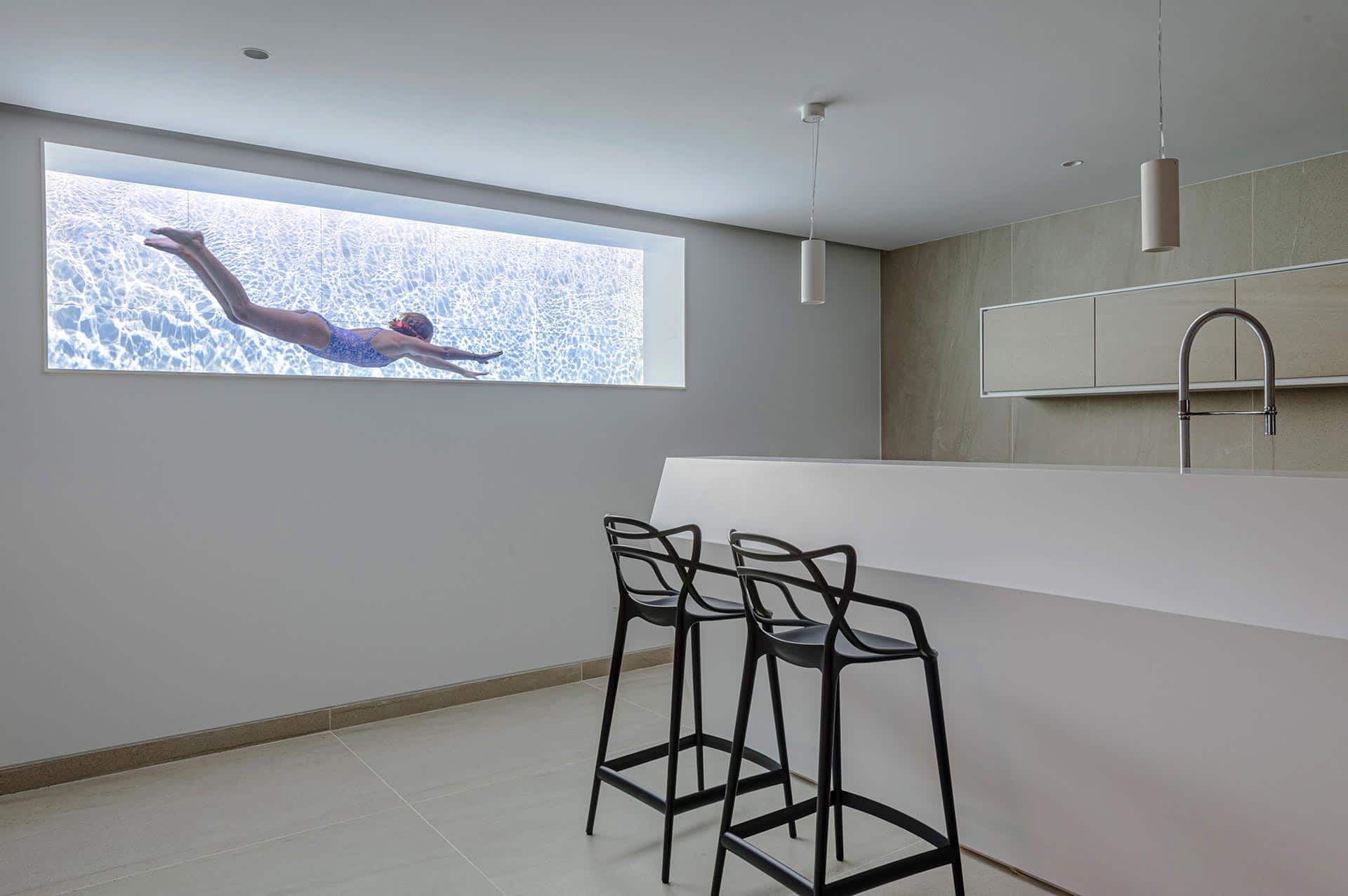 Barra de bar y ventana hacia piscina en casa moderna diseñada por Moah Arquitectos en Cantabria