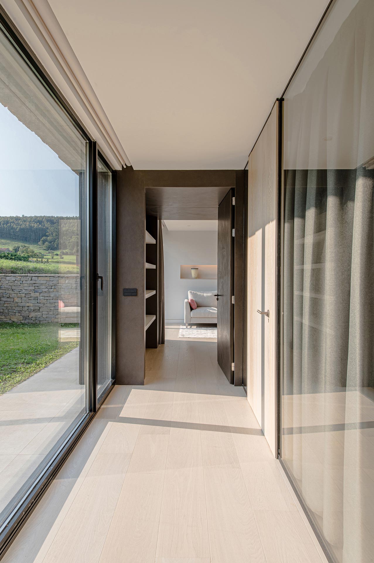 Pasillo con grandes cristaleras de casa moderna diseñada por Moah Arquitectos en Cantabria