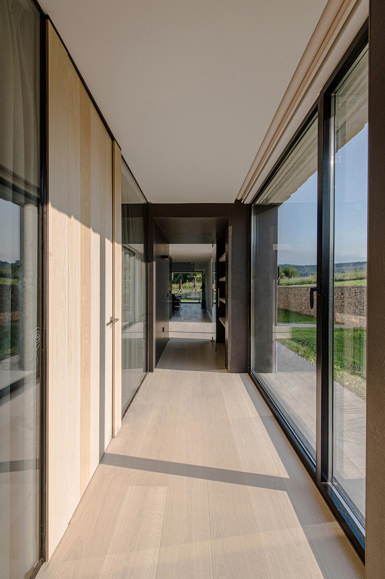 Pasillo con grandes cristaleras en casa moderna diseñada por Moah Diseñadores de Interiores en Cantabria