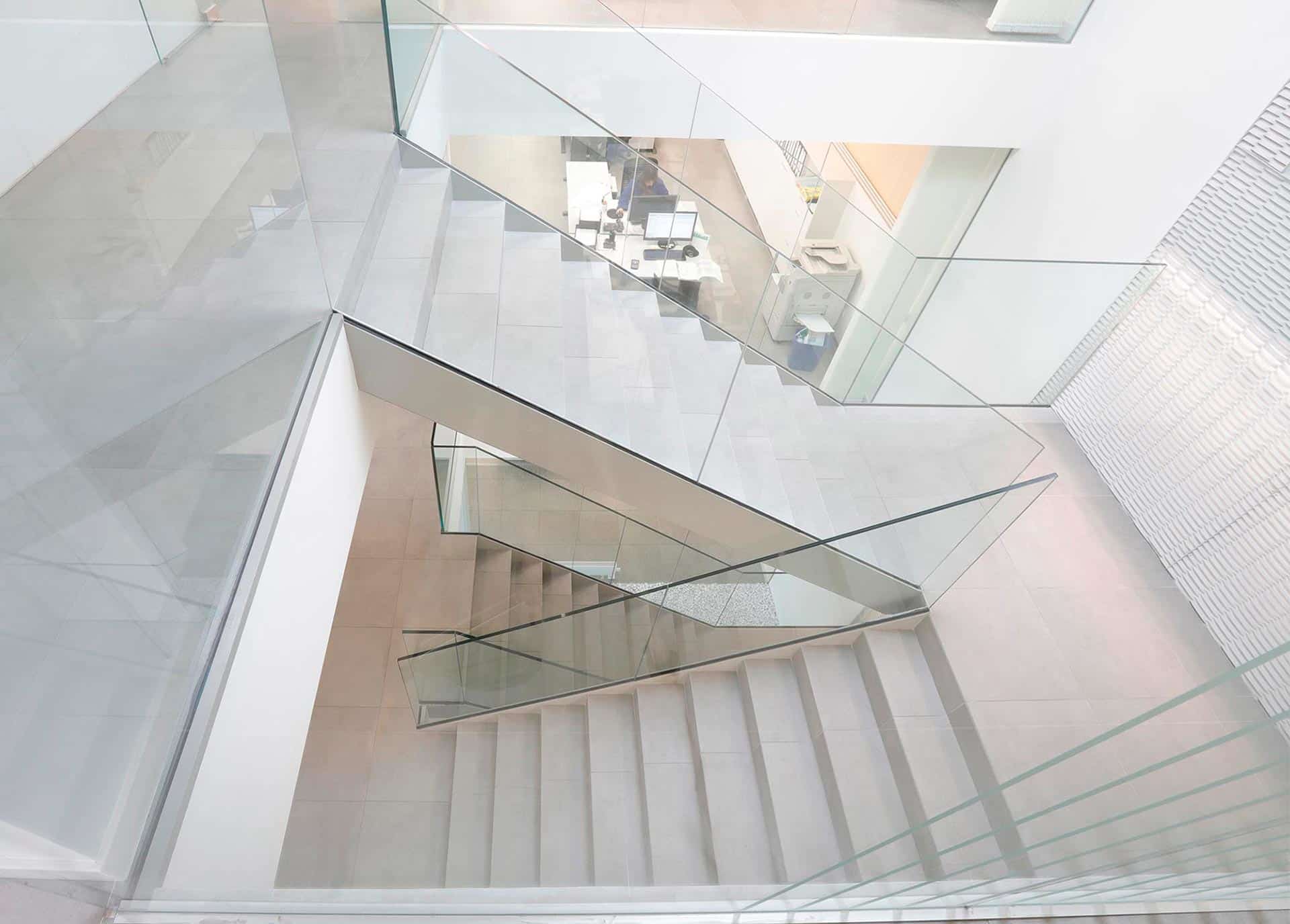 Escaleras con varadilla de cristal en reforma de oficina de diseño diseñada por Moah Arquitectos en Cantabria
