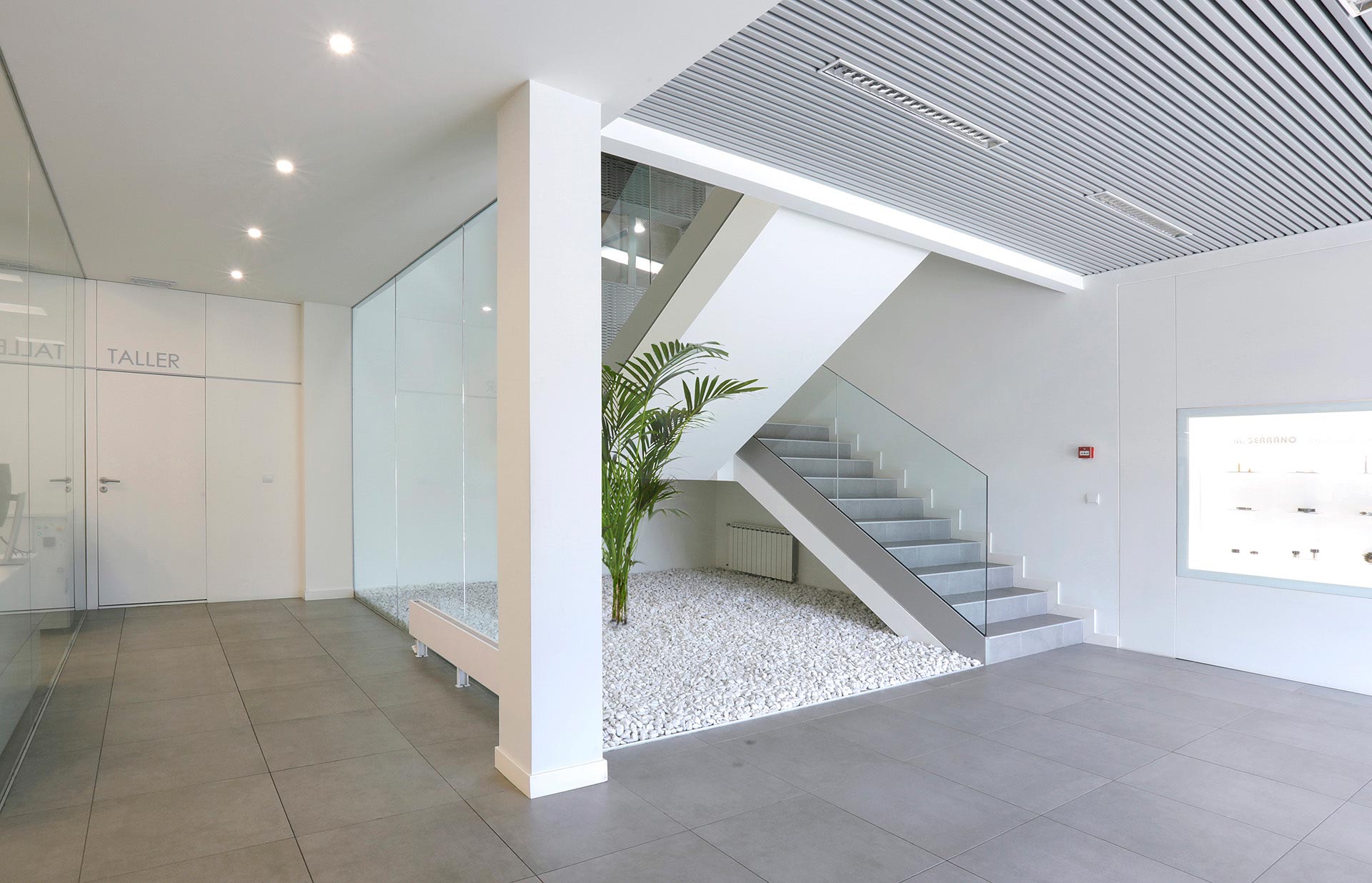 Vestíbulo con escalera y lamas en reforma integral de oficina diseñada por Moah Arquitectos en Cantabria