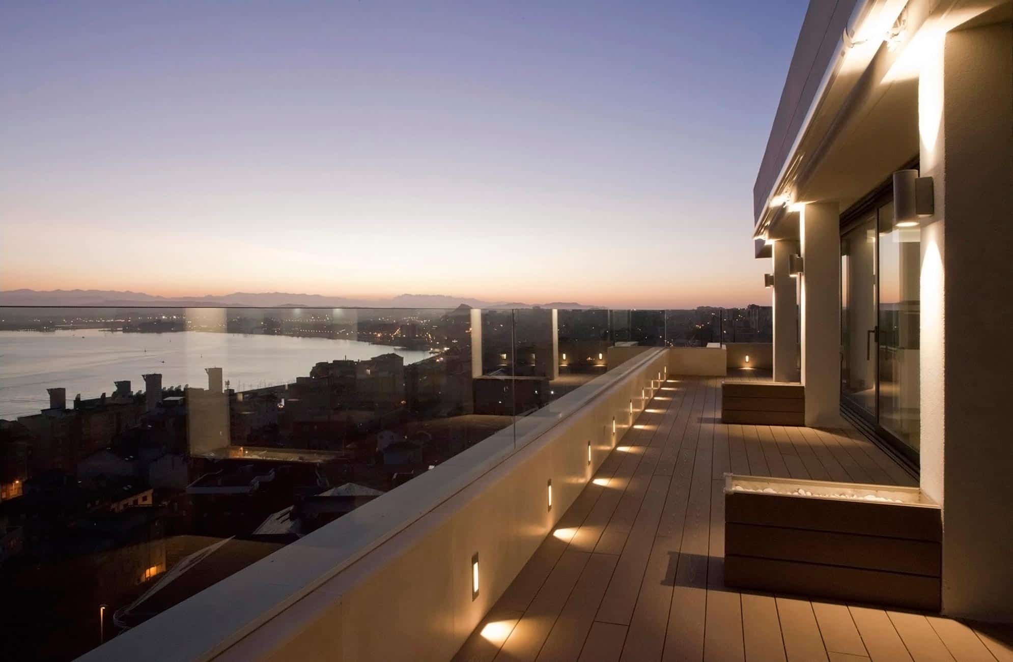 Terraza con iluminación nocturna en ático de lujo diseñado por Moah Diseño de Interiores en Santander