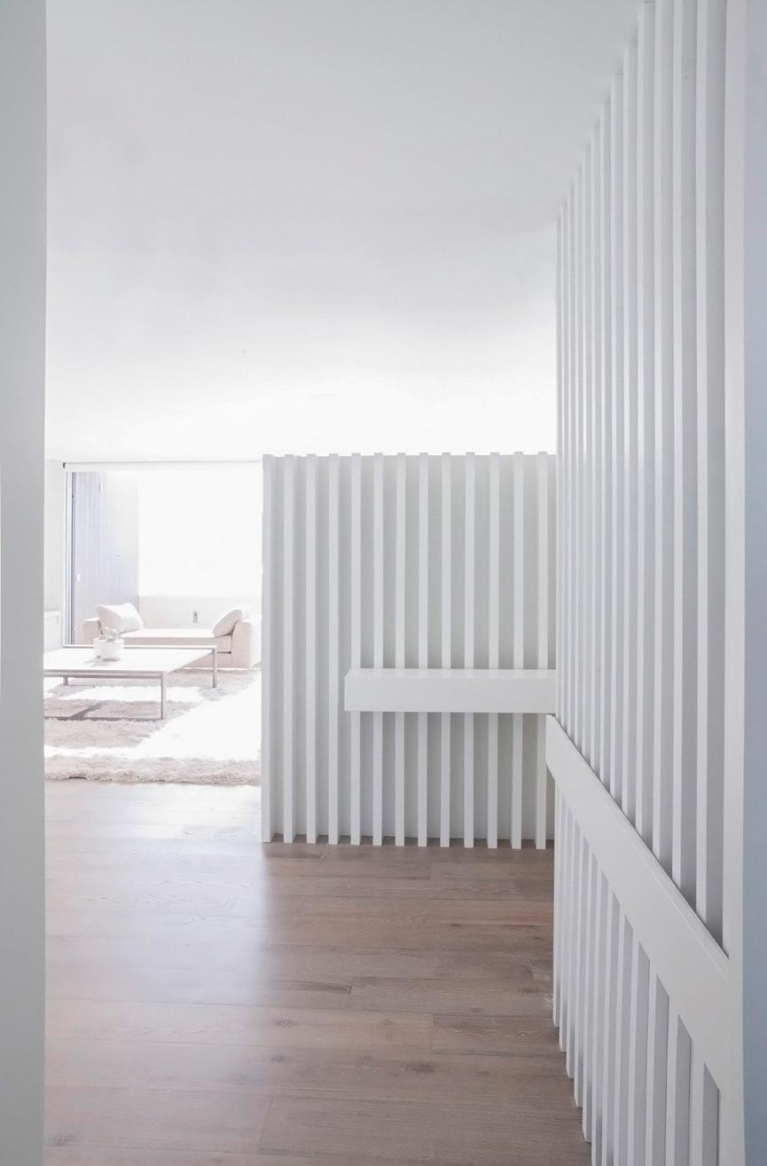Vestíbulo de diseño con lamas blancas en reforma integral de vivienda diseñada por Moah Arquitectos en Santander