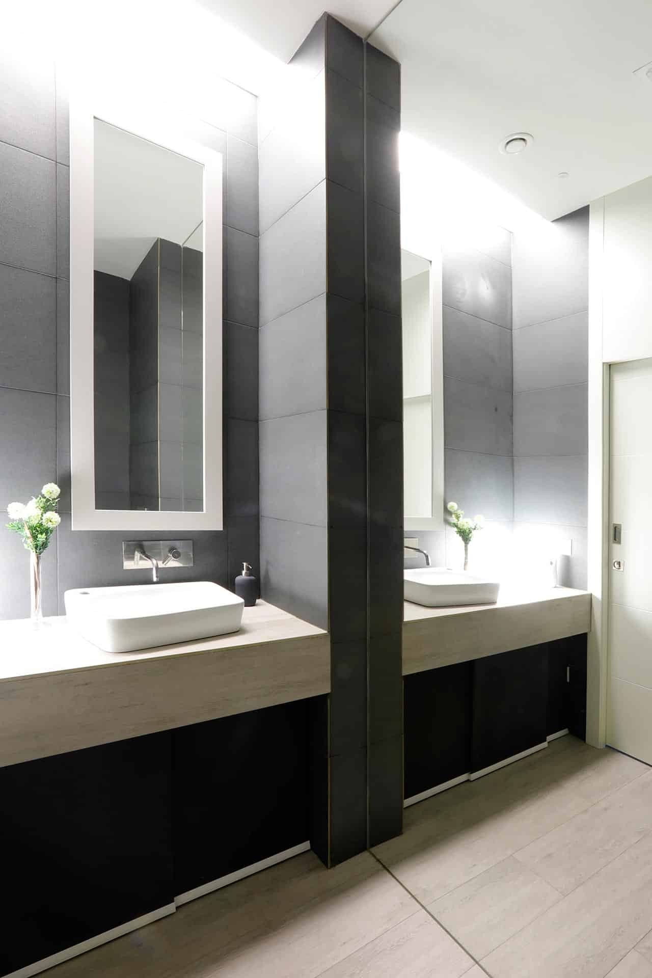 Baño de local de diseño con gres porcelánico negro y gran espejo diseñado por Moah Arquitectos en Santander
