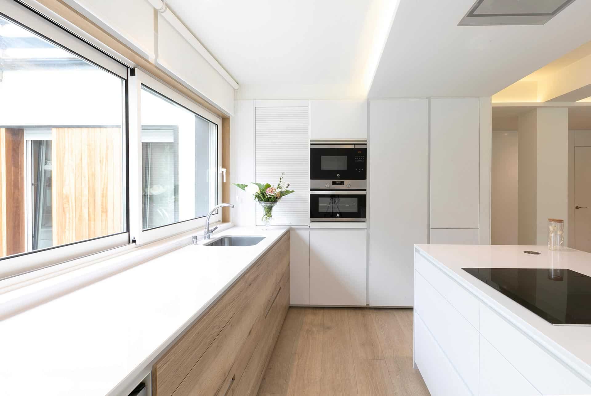 Cocina abierta al salón en reforma de vivienda con interiorismo diseñada por Moah Arquitectos en Cantabria
