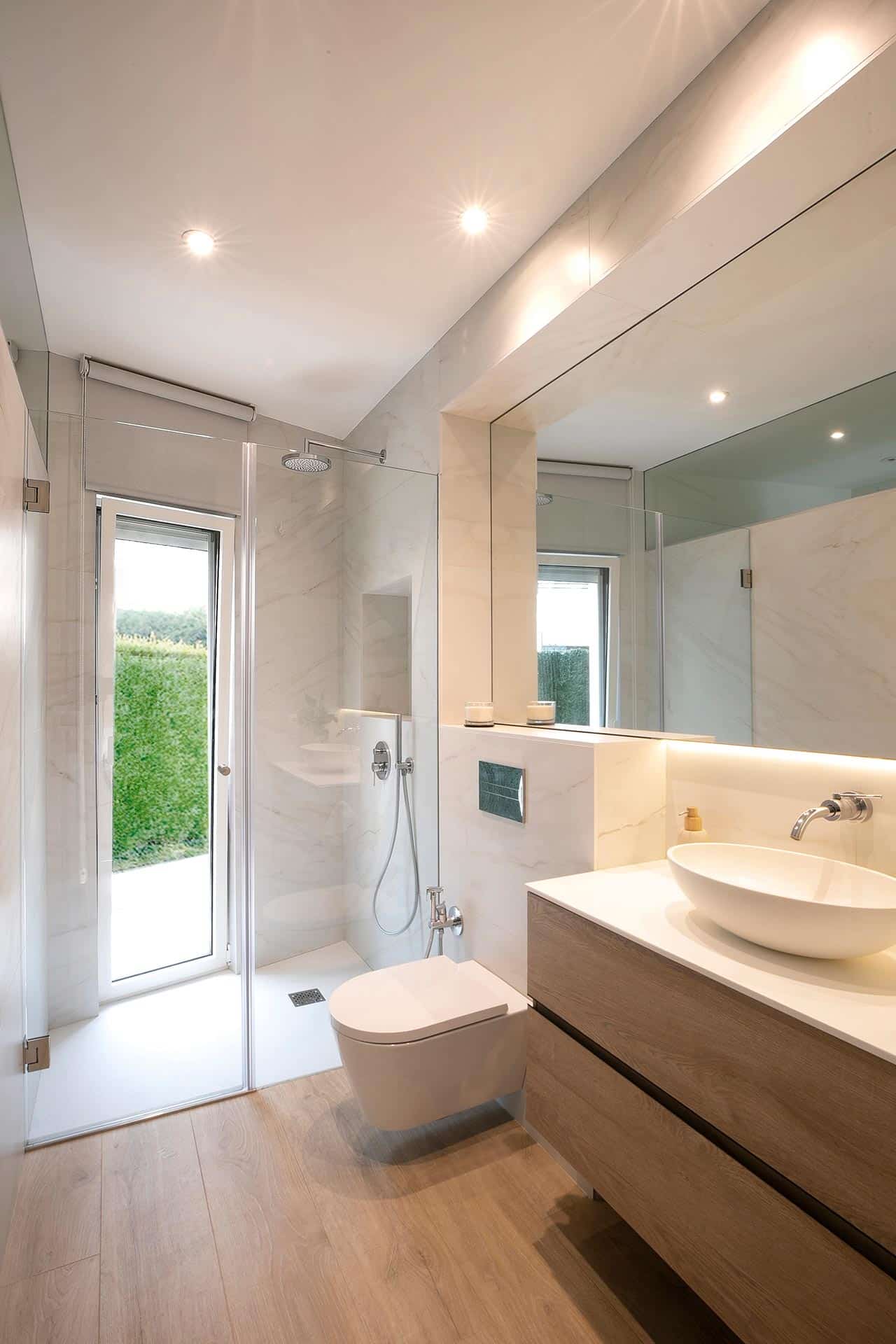 Baño blanco tono mármol con espejo en reforma de vivienda de diseño diseñada por Moah Arquitectos en Cantabria