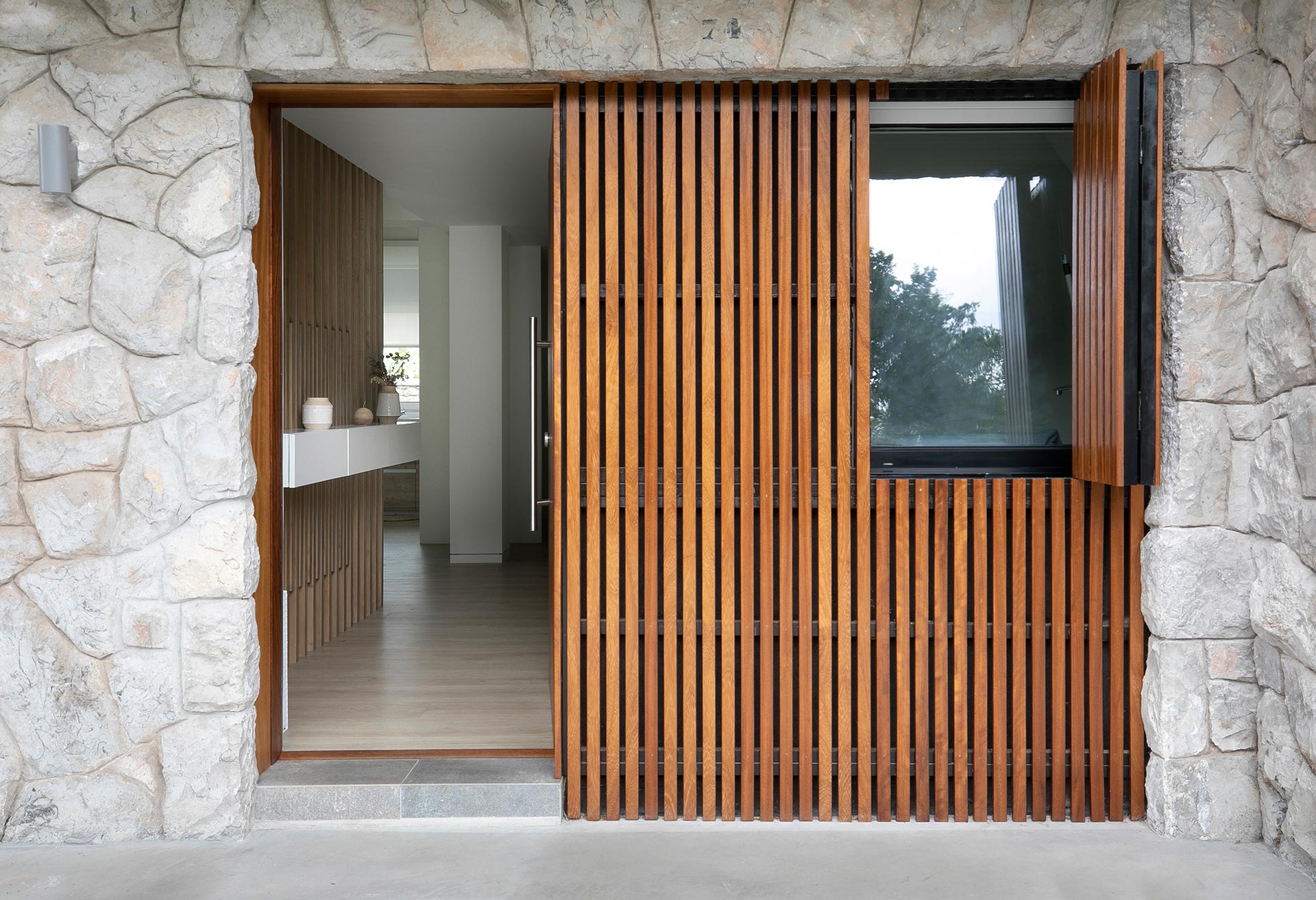 Fachada con lamas de madera pivotantes en reforma de vivienda moderna diseñada por Moah Arquitectos en Sarón