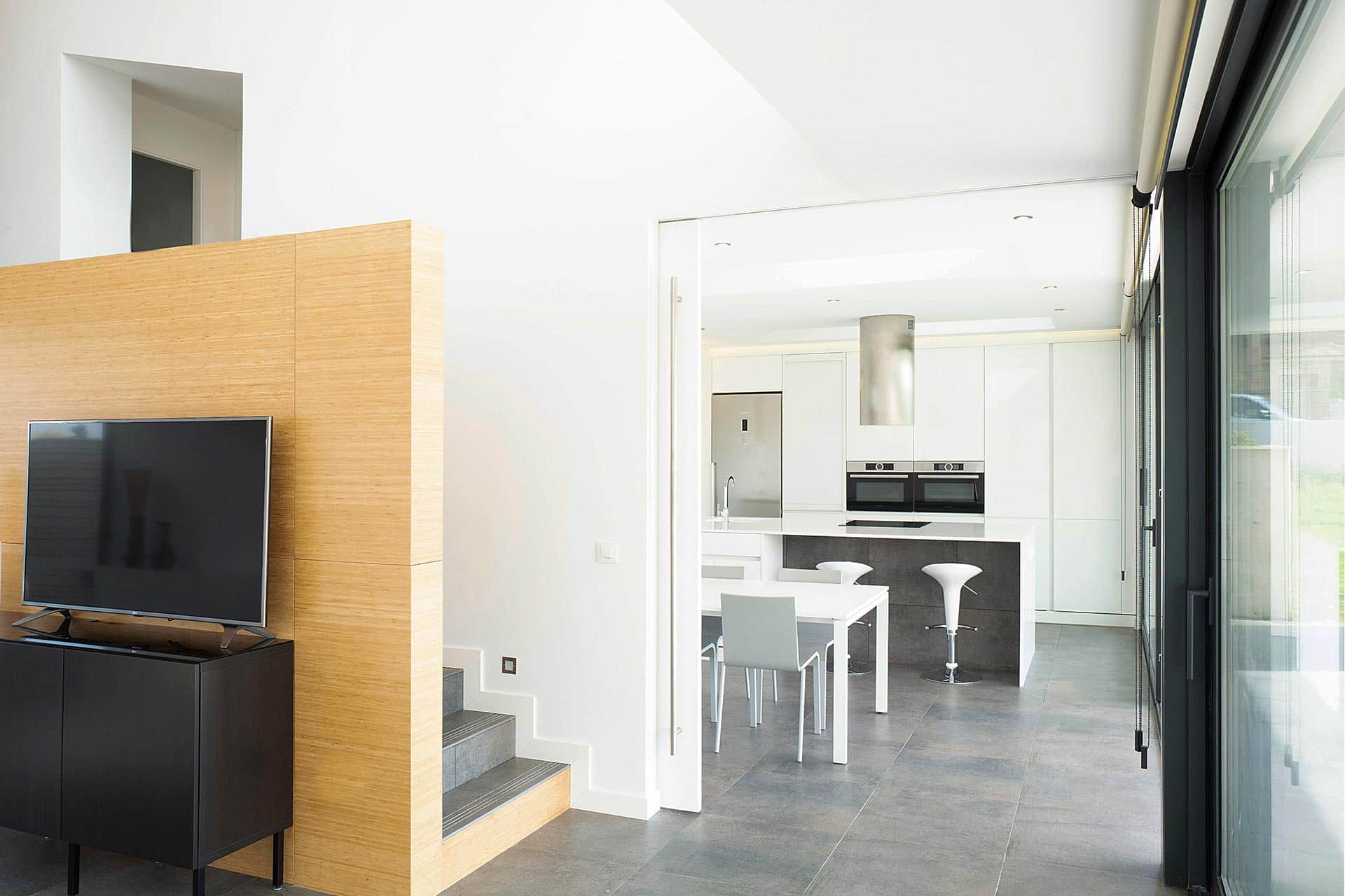 Cocina blanca conectada a salón en casa moderna diseñada por Moah Arquitectos en Villaverde, Cantabria