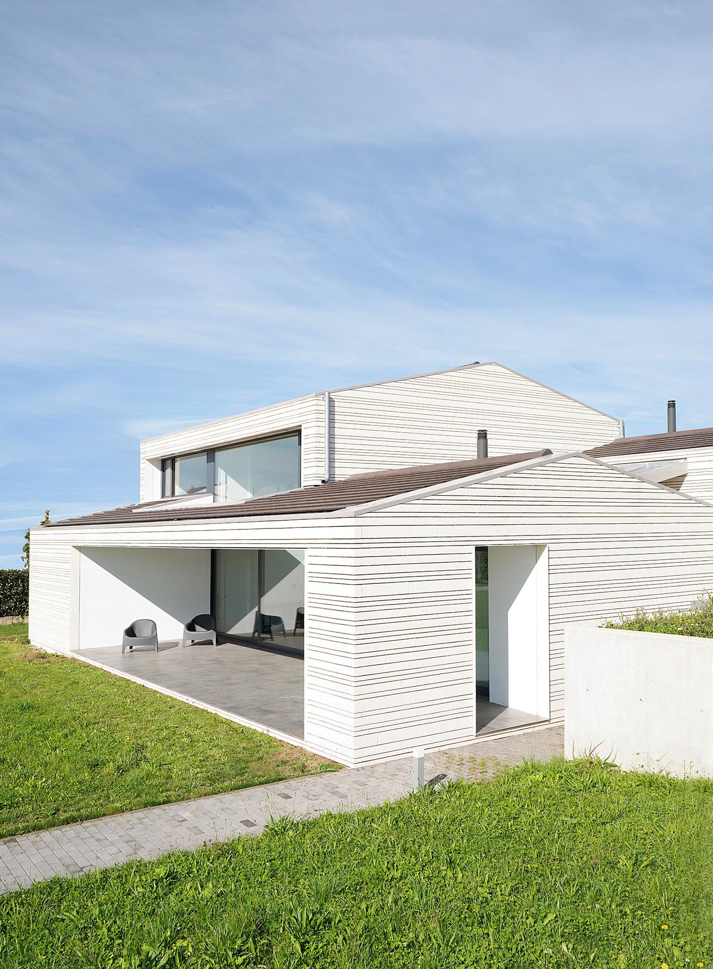 Casa en ladrillo blanco y grandes ventanales diseñada por Moah Arquitectos en Villaverde, Cantabria
