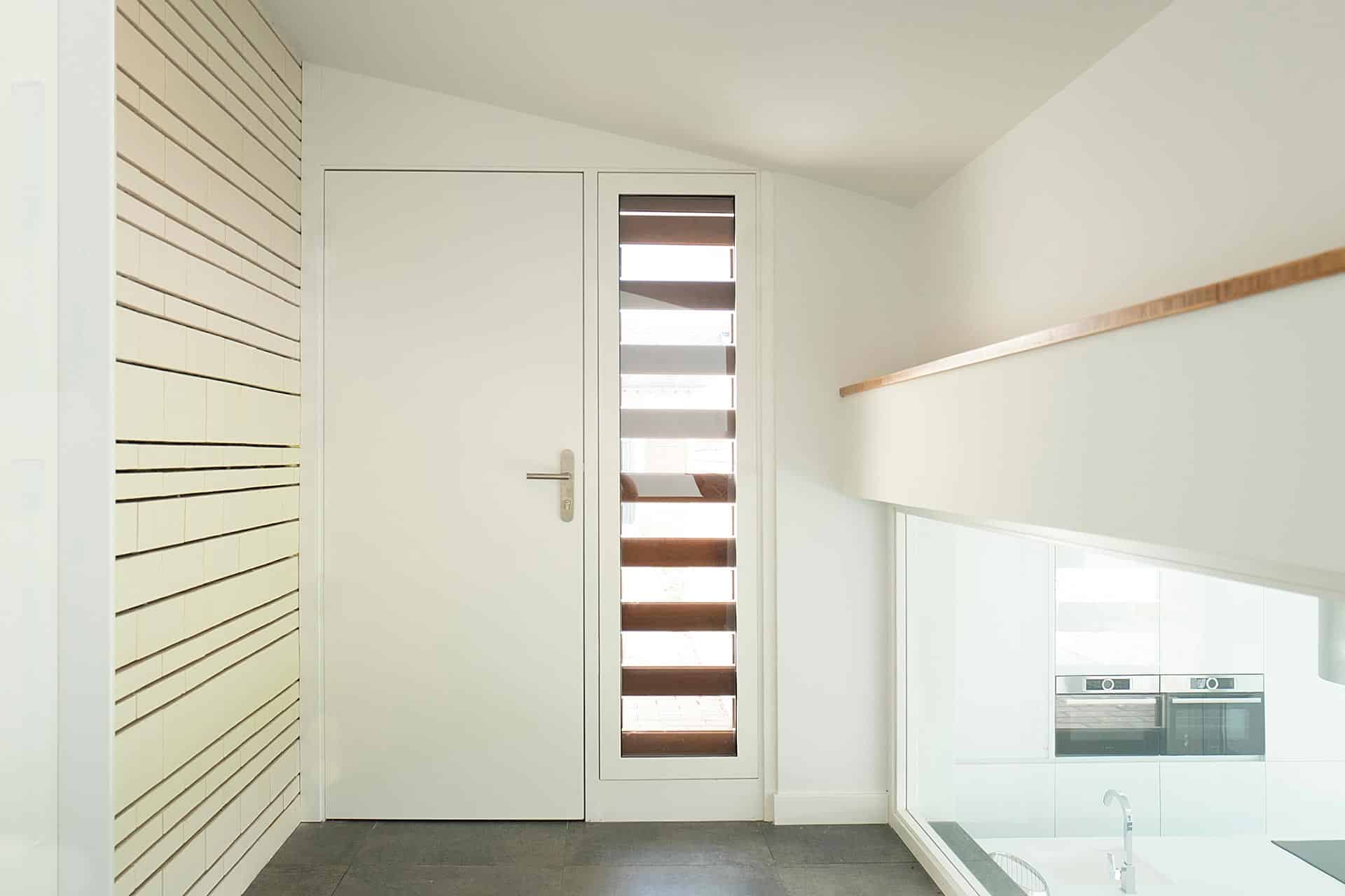 Vestíbulo de acceso blanco diseñado por Moah Arquitectos en Cantabria