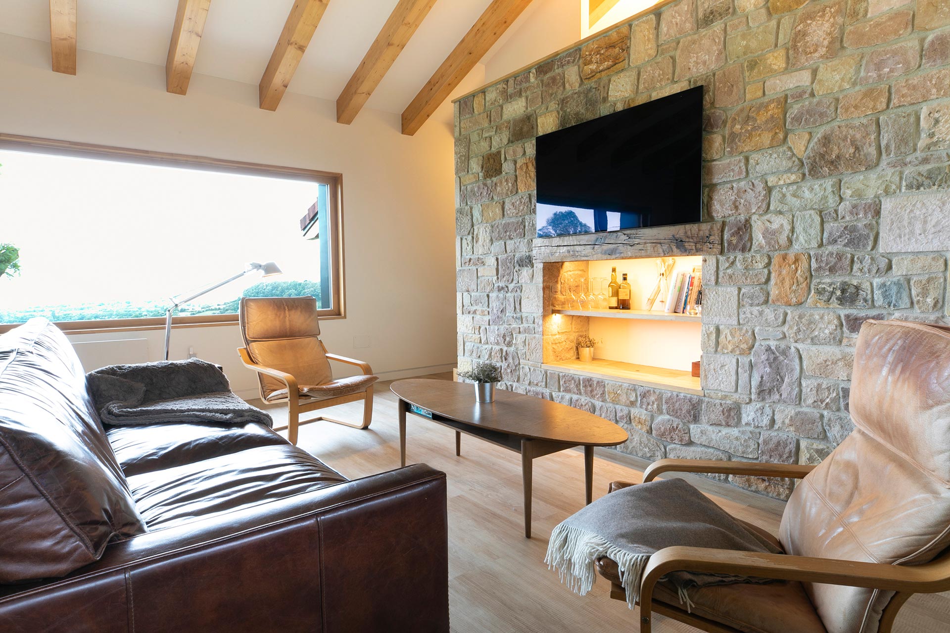 Salón con piedra y madera en alojamiento rural moderno en Proaño diseñada por Moah Arquitectos en Cantabria