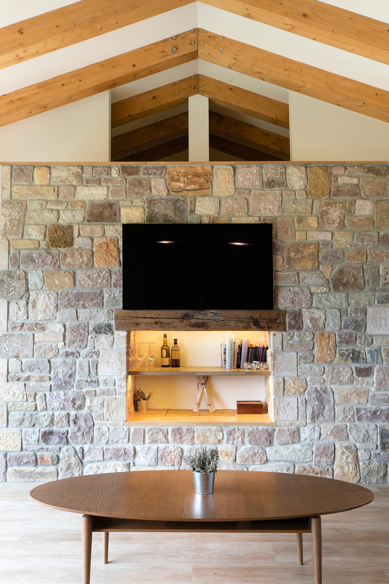 Salón con piedra y madera en casa rural moderna en Proaño diseñada por Moah Arquitectos en Cantabria