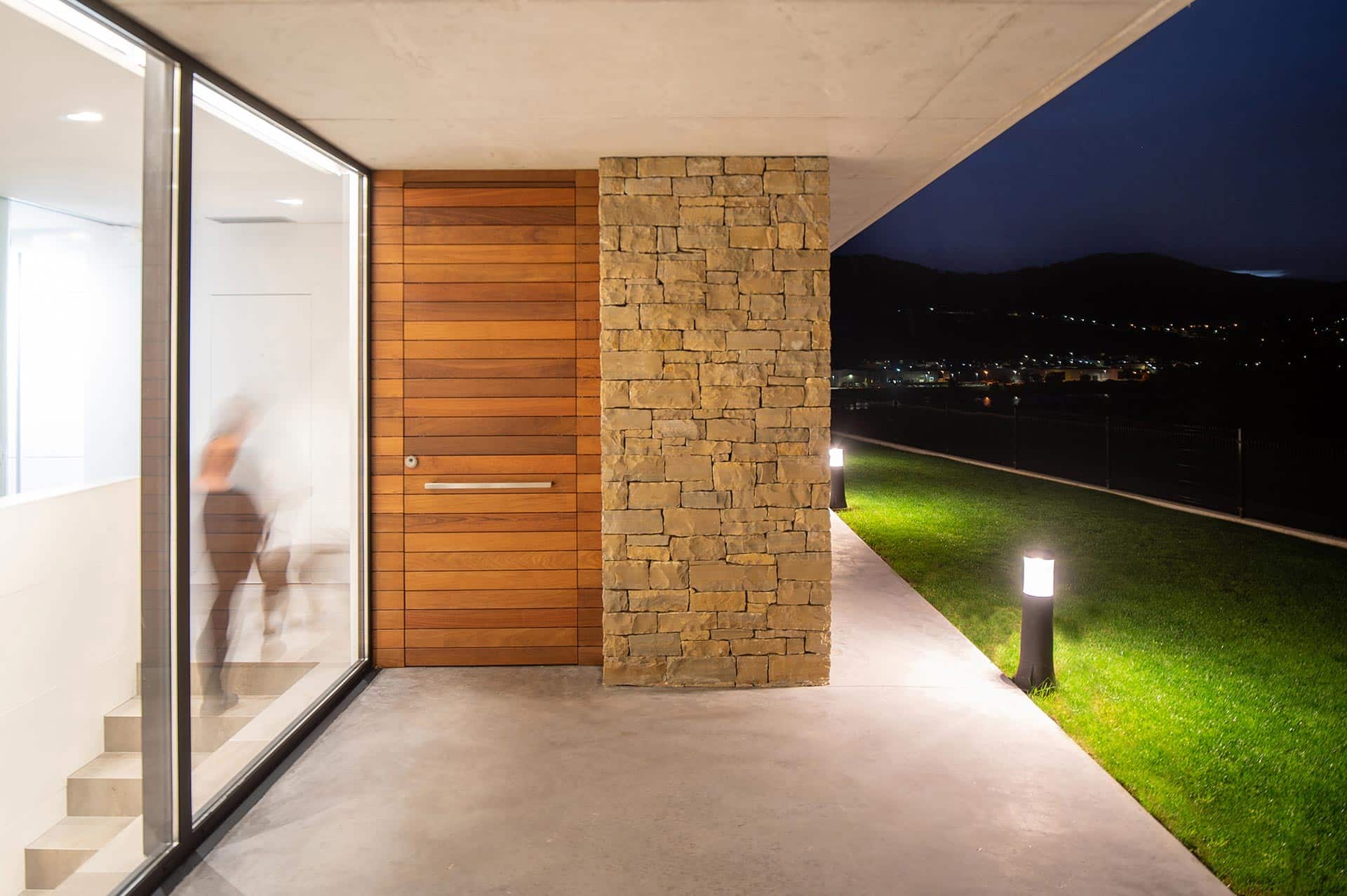 Puerta de entrada de madera en casa moderna diseñada por Moah Arquitectos en Pontejos