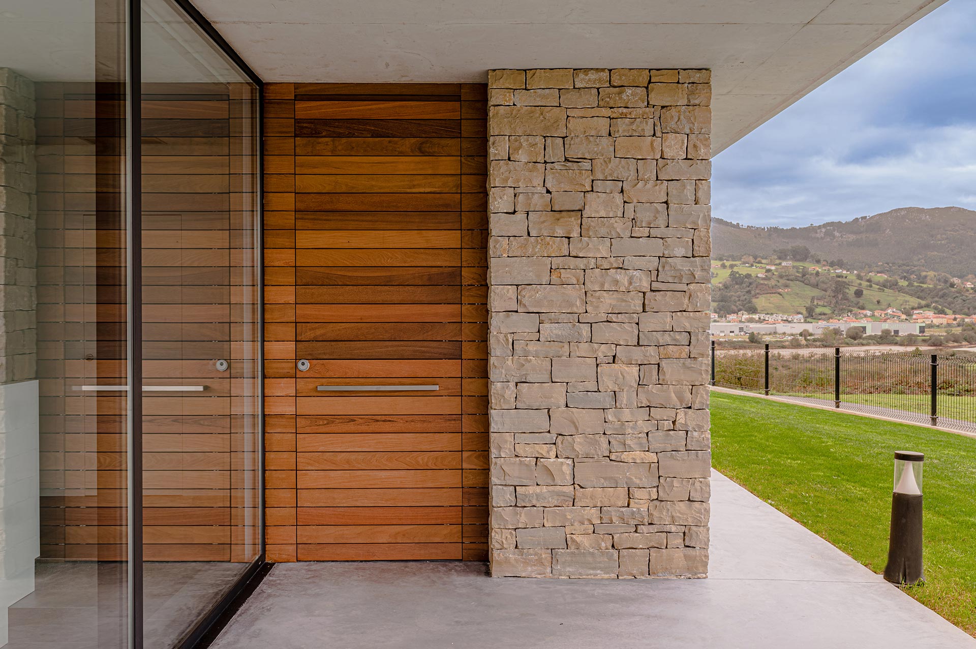 Puerta de entrada de madera de casa moderna diseñada por Moah Arquitectos en Pontejos