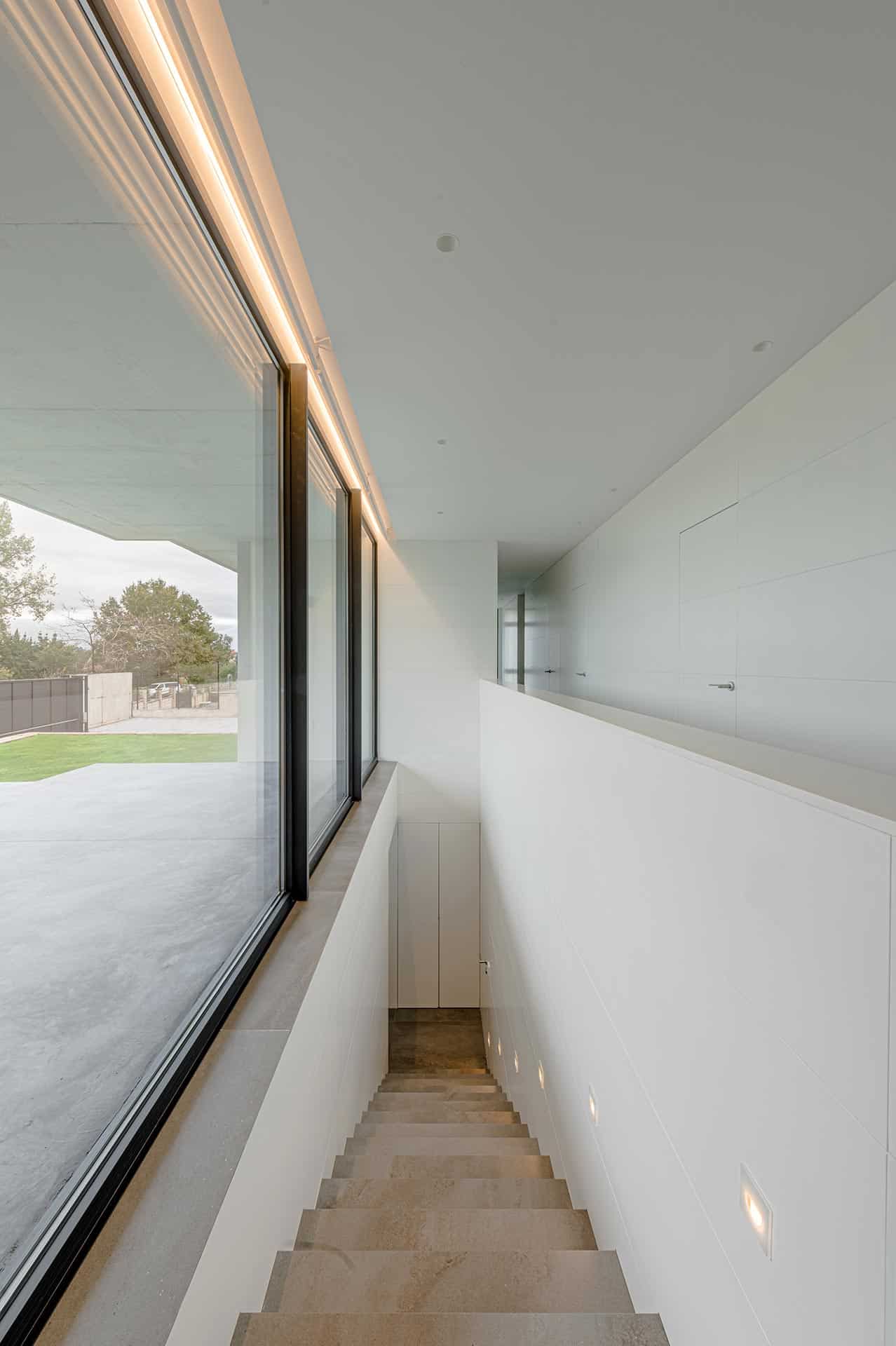 Escalera con grandes cristaleras en casa moderna diseñada por Moah Arquitectos en Pontejos