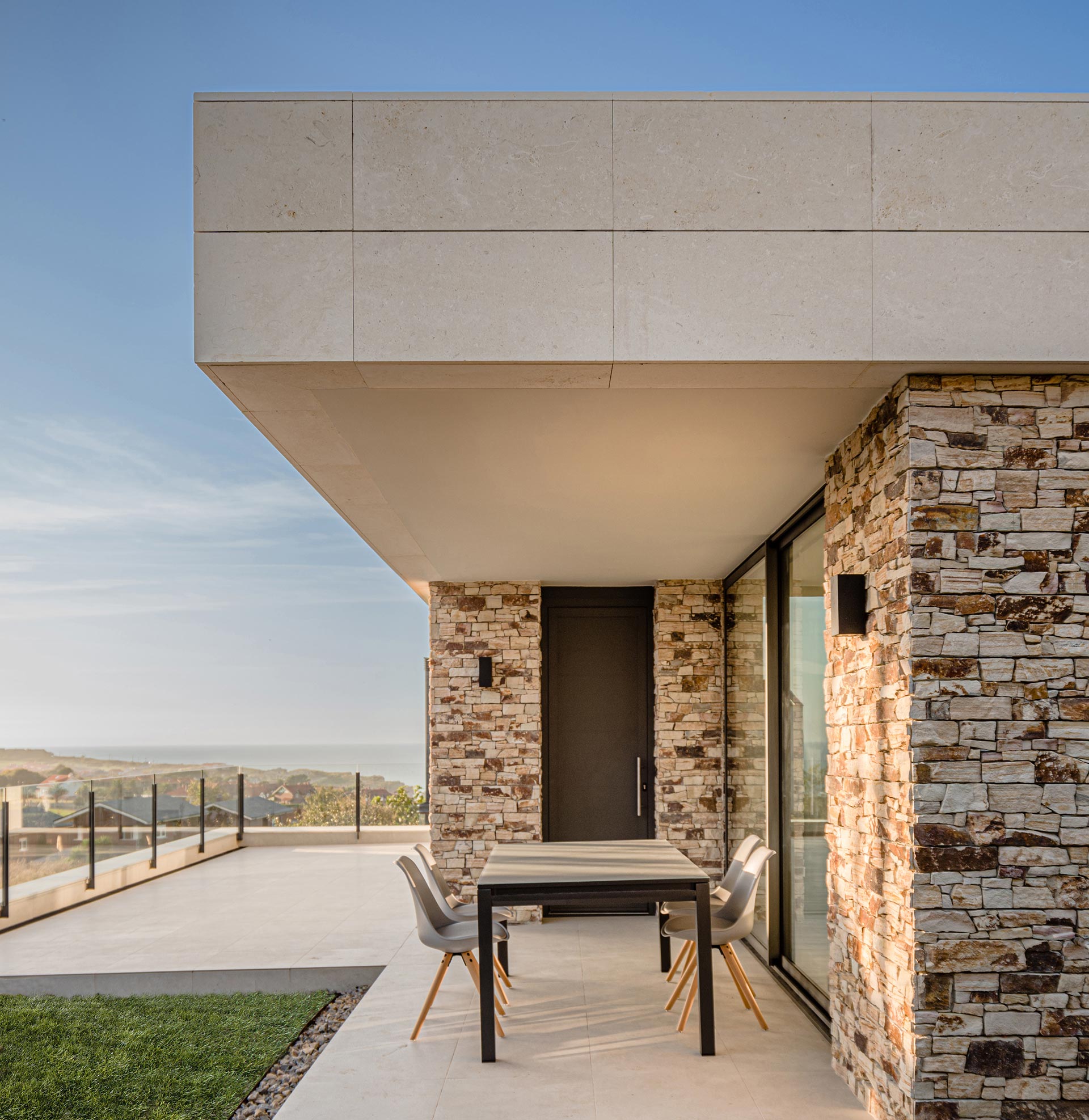 Porche de casa moderna con piedra stone panel y piedra blanca diseñada por Moah Arquitectos en Piélagos. Cantabria
