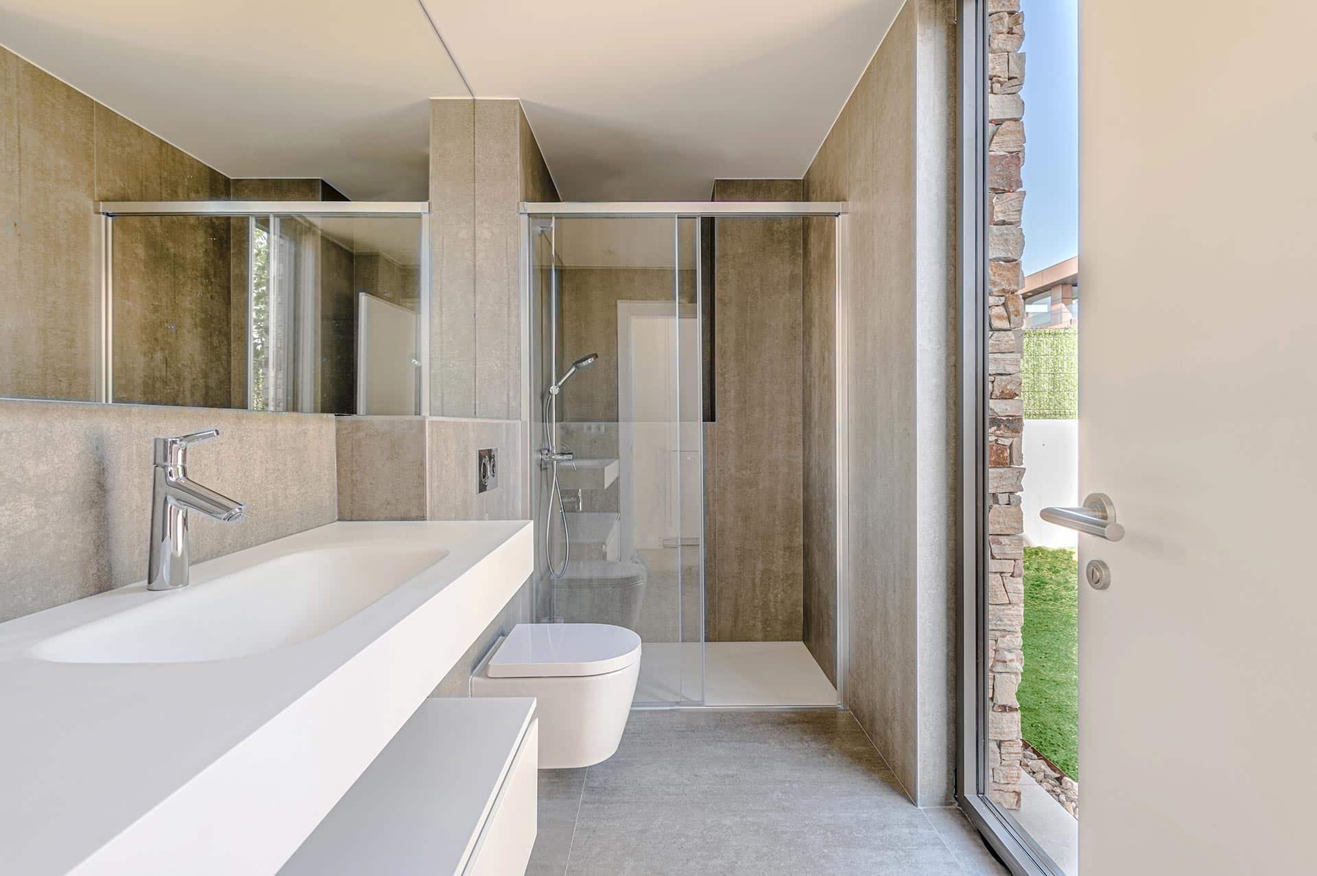 Baño minimalista con gres porcelanico gris en vivienda diseñada por Moah Arquitectos en Piélagos. Cantabria