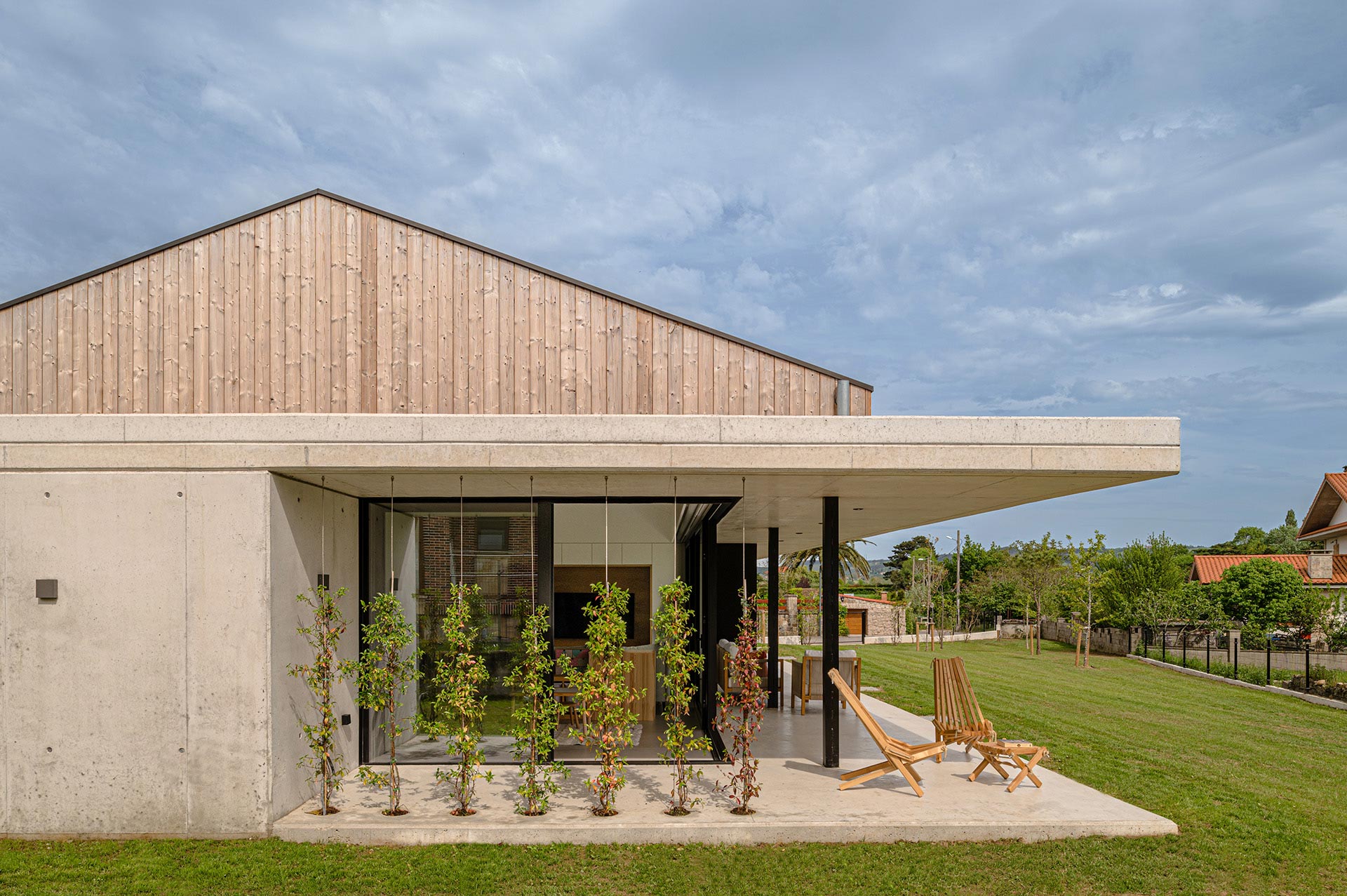 Exterior de casa de hormigón y madera diseñada por Moah Arquitectos en Suesa. Cantabria.
