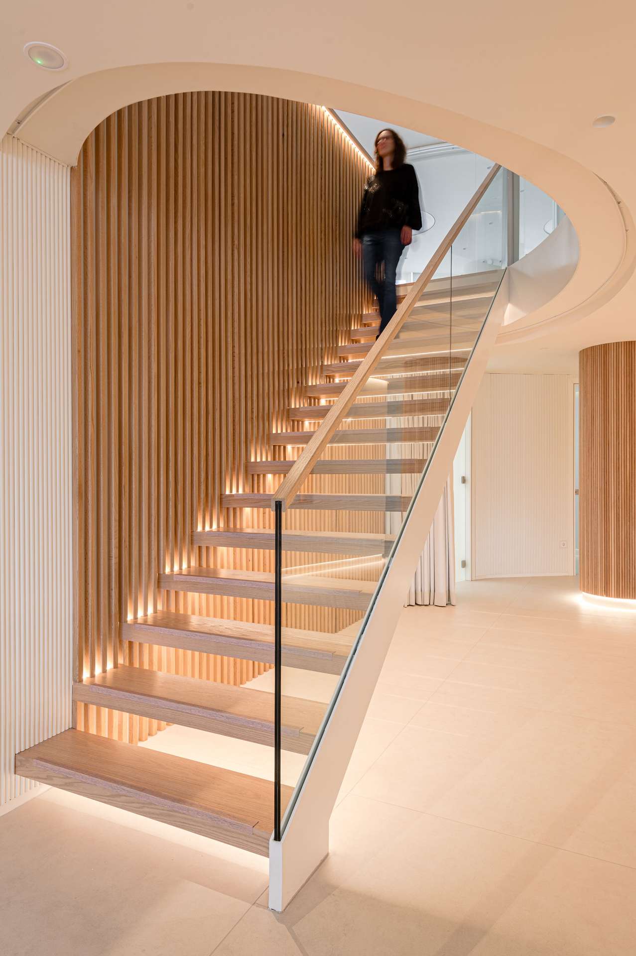 Escalera helicoidal con iluminación integrada y detalles en madera, diseñada por Moah Arquitectos en Santander.