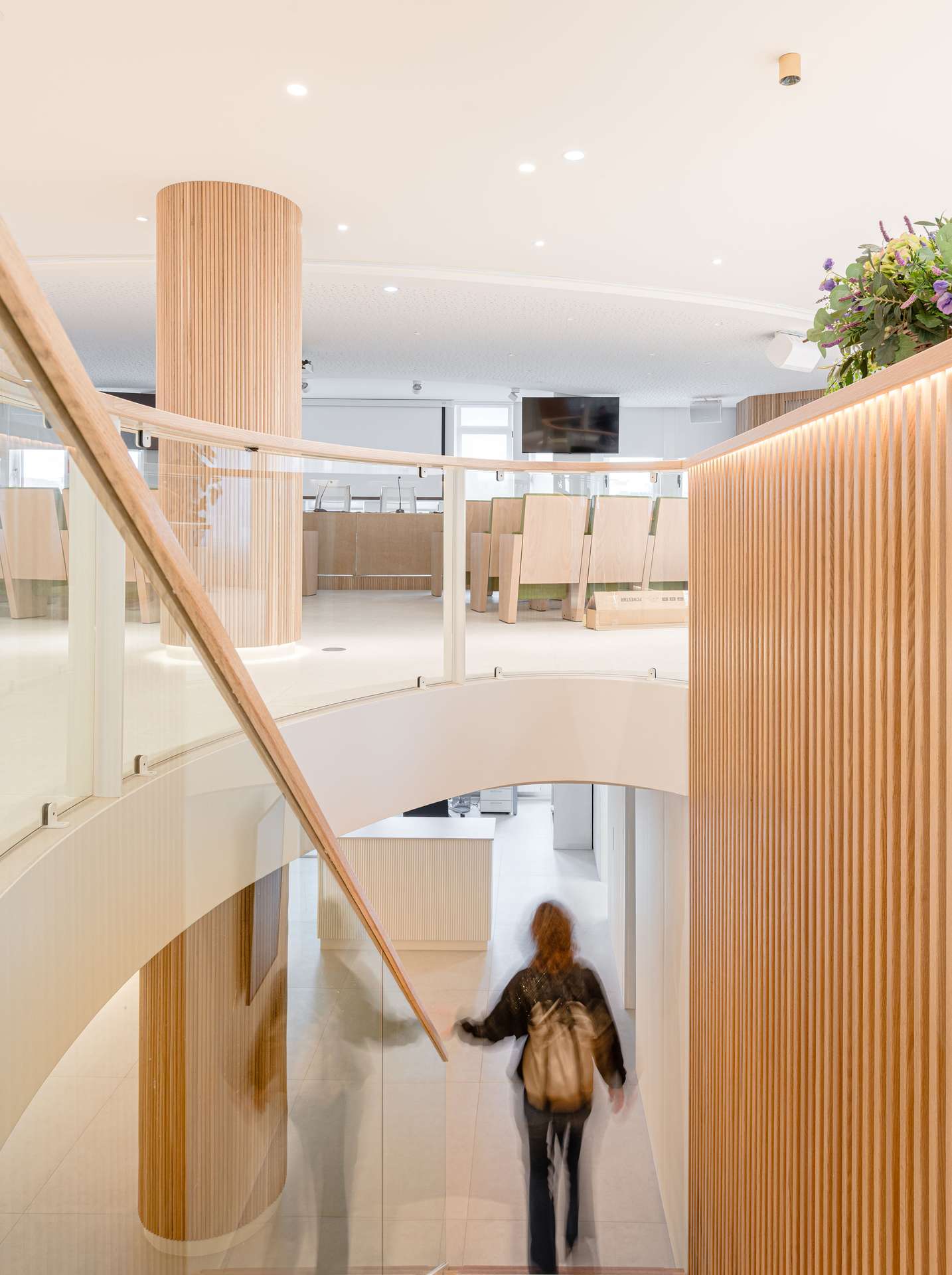 Vestíbulo de entrada con una elegante escalera helicoidal y detalles en madera, concebido por Moah Arquitectos en Santander.
