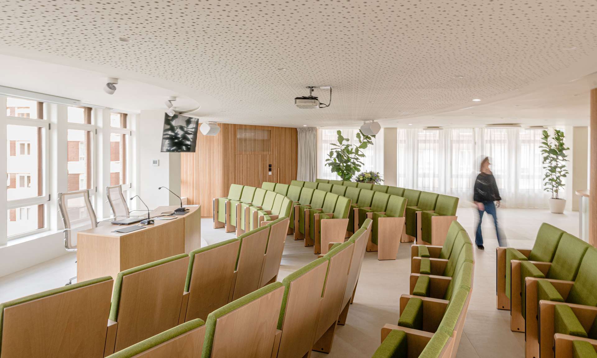 Espacio moderno con asientos curvos en tonos verdes y madera, concebido por Moah Arquitectos en Santander.