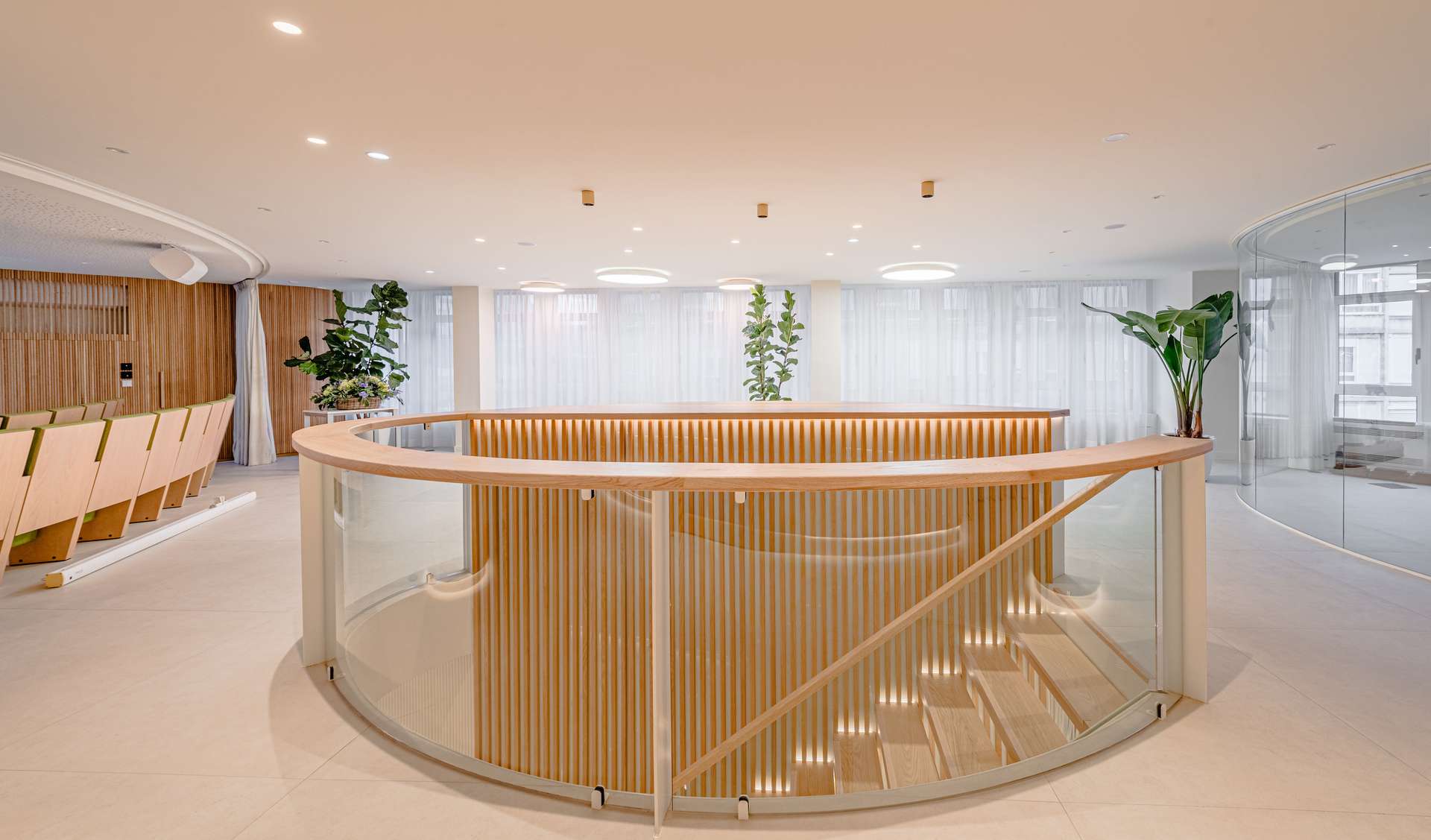 Vestíbulo de entrada con una elegante escalera helicoidal y detalles en madera, concebido por Moah Arquitectos en Santander.
