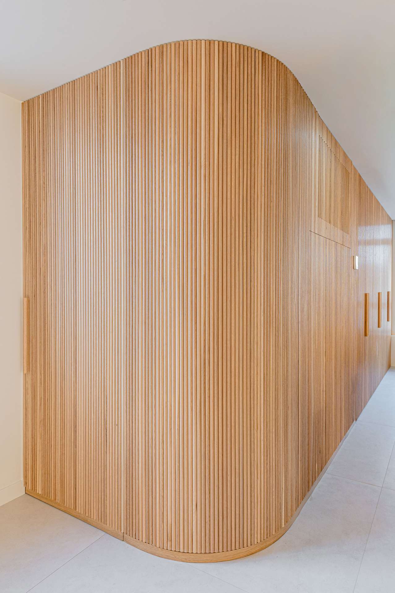 Detalle de una pared curvada y texturizada en madera, diseñada por Moah Arquitectos en Santander.